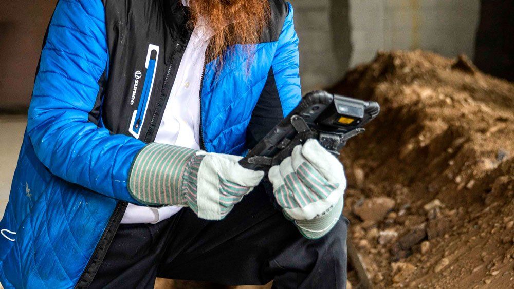 worker wearing gloves at construction site holds sonim rs80 tablet
