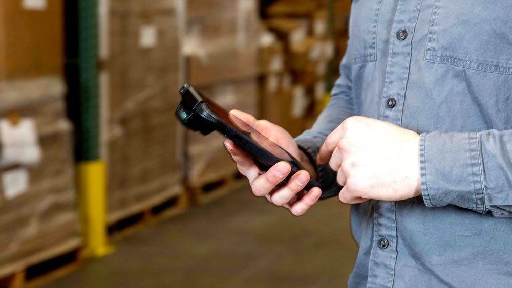 worker in warehouse using mobile computer with barcode scanner