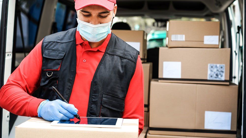 Worker in front of full delivery van uses stylus and tablet