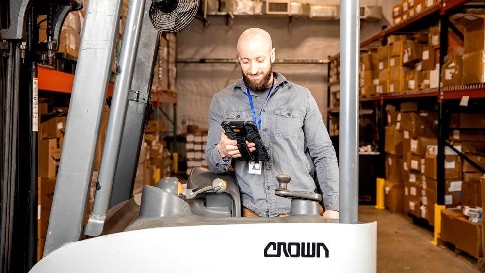 worker in forklift at warehouse uses sonim rs80 tablet