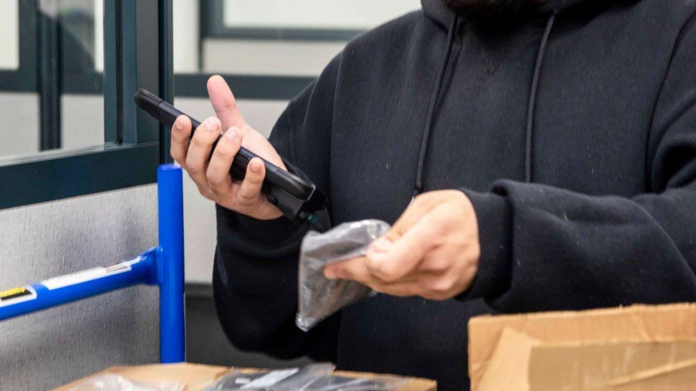 worker wearing black hoodie uses mobile computer barcode scanner