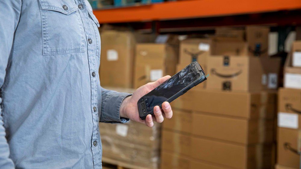 worker in warehouse uses Sonim RS60 for inventory
