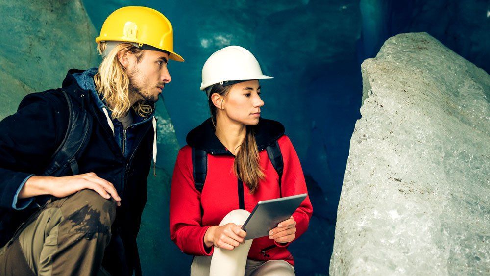 scientists wearing hard hats cataloguing stone using rugged tablet