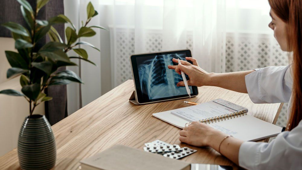 woman sitting at office table uses upright tablet for medical imaging