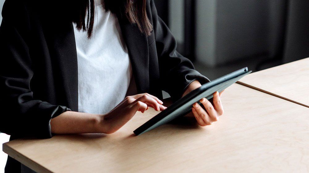 woman in business attire using tablet at table