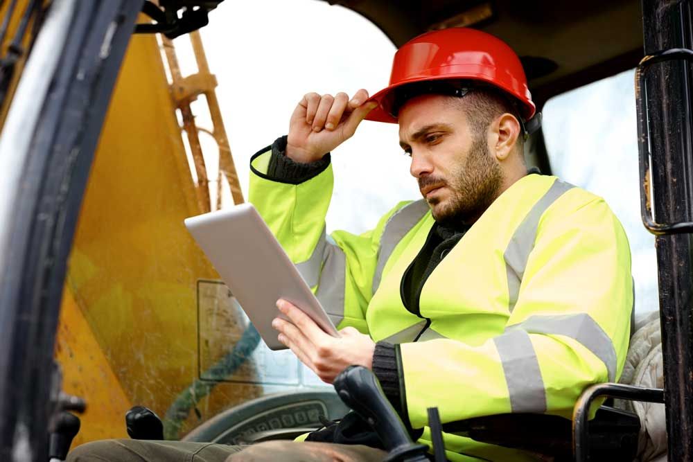 Construction Worker in tractor using tablet