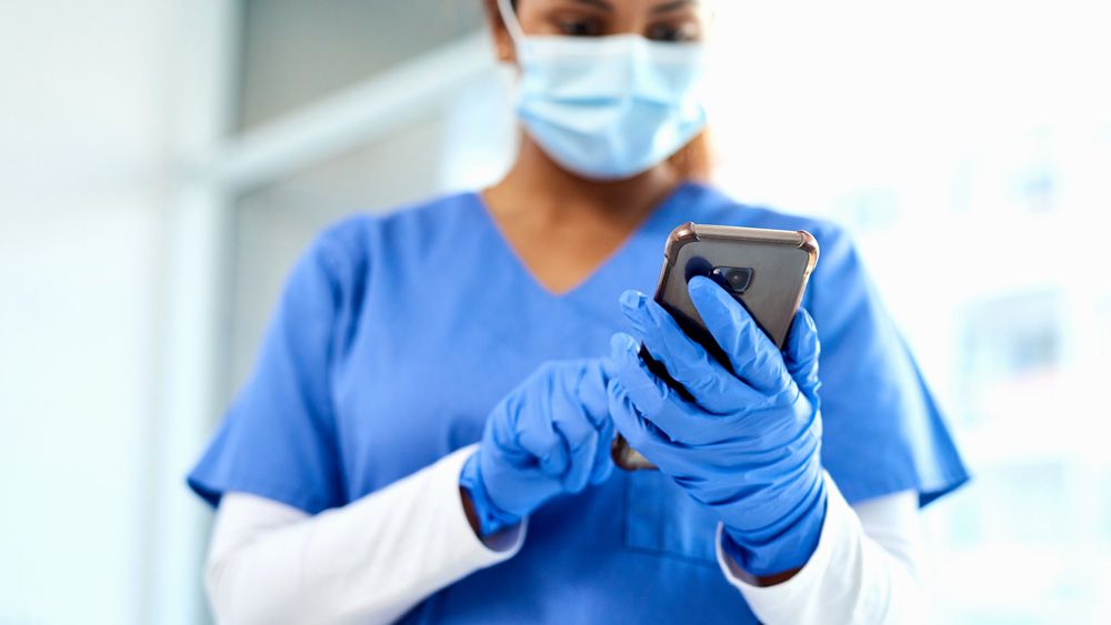 Nurse with gloves using rugged medical phone in hospital