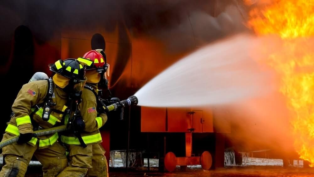 firefighters fighting fire hose and tech