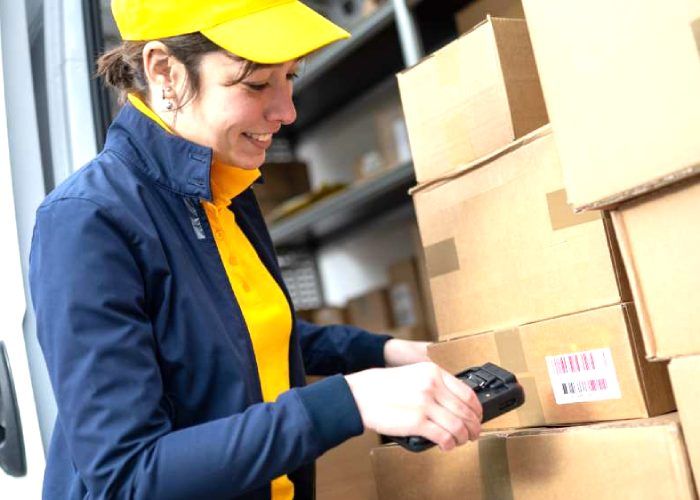 A woman wearing a yellow cap scanning a code in a box
