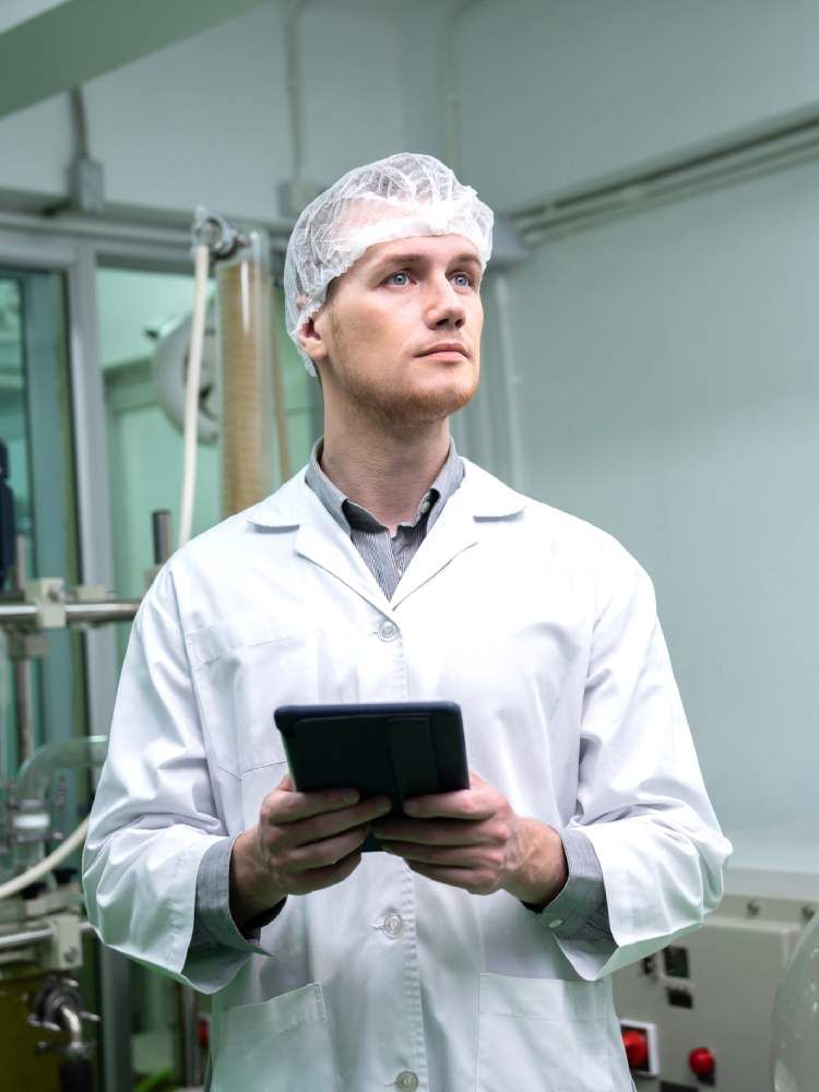 A man wear a lab gown holds a black tablet