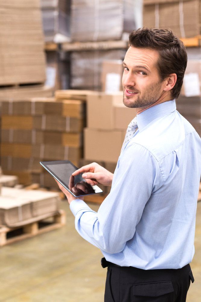 A man with a beard is operating a tablet inside a warehouse
