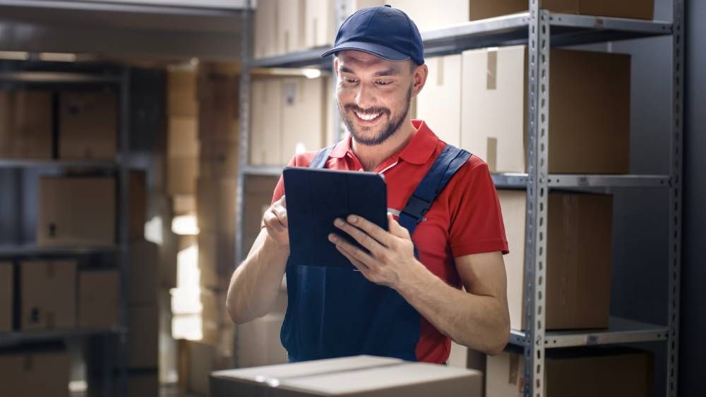 A smiling worker man holds a black tablet