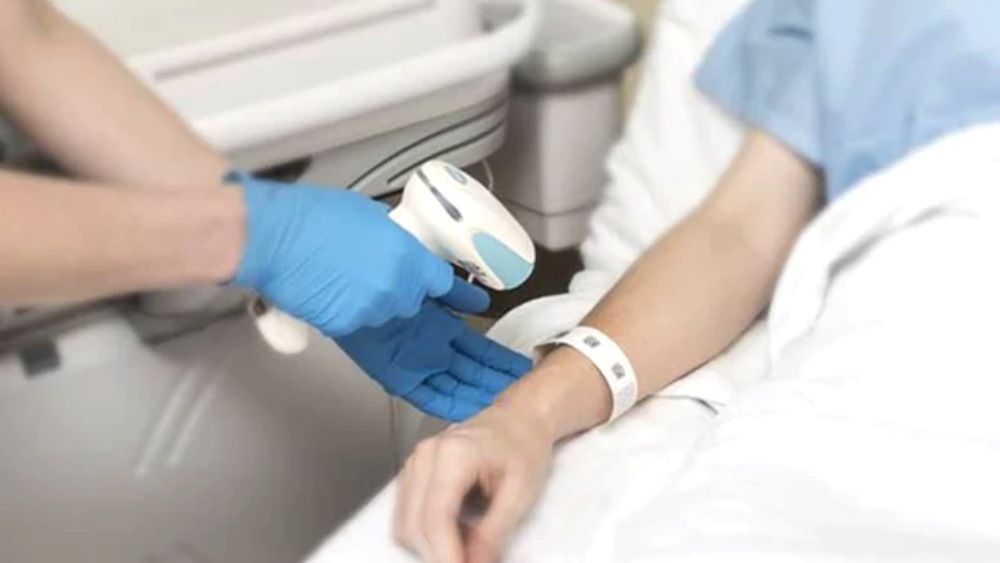 A healthcare worker is scanning patient wrist band
