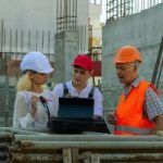 three construction workers were talking in front of a tablet