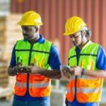 two manufacturer workers uses a phone while at work