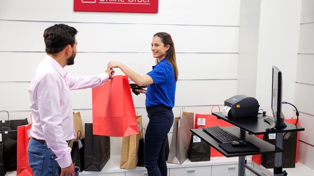 Saleswoman hands the customer the red shopping bag