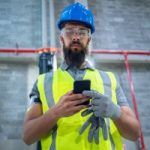 worker who took off one of his gloves and then looking at his phone